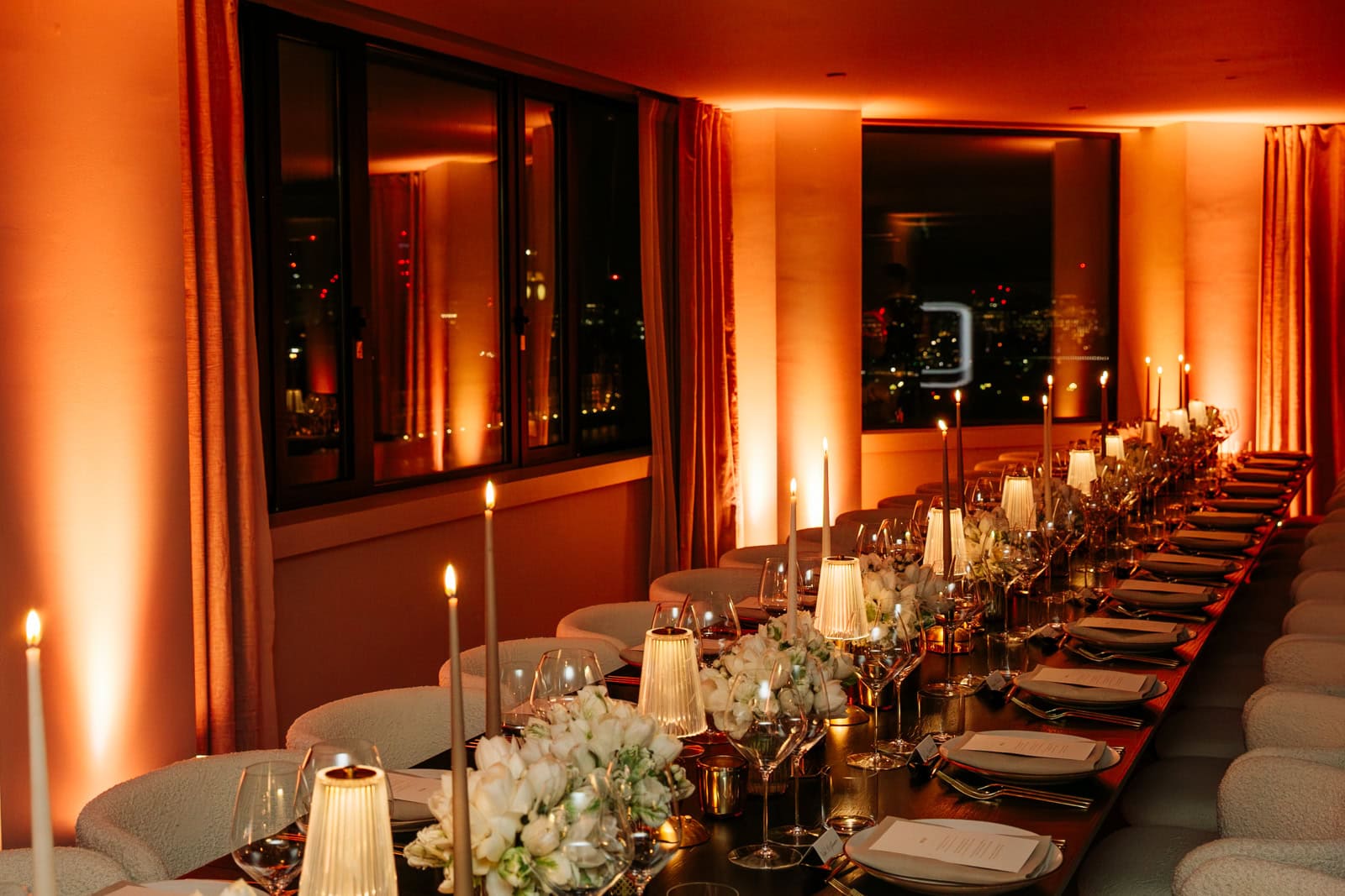 A long private dining table set with flowers and candles