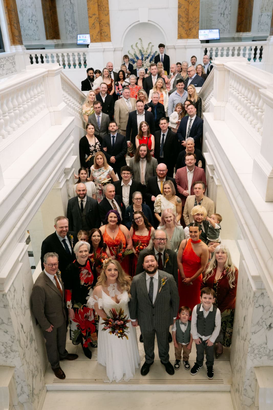 All the guests lining up for a group shot on the staircase at Camden Town Hall ceremony London — Nick Tucker London wedding photographer