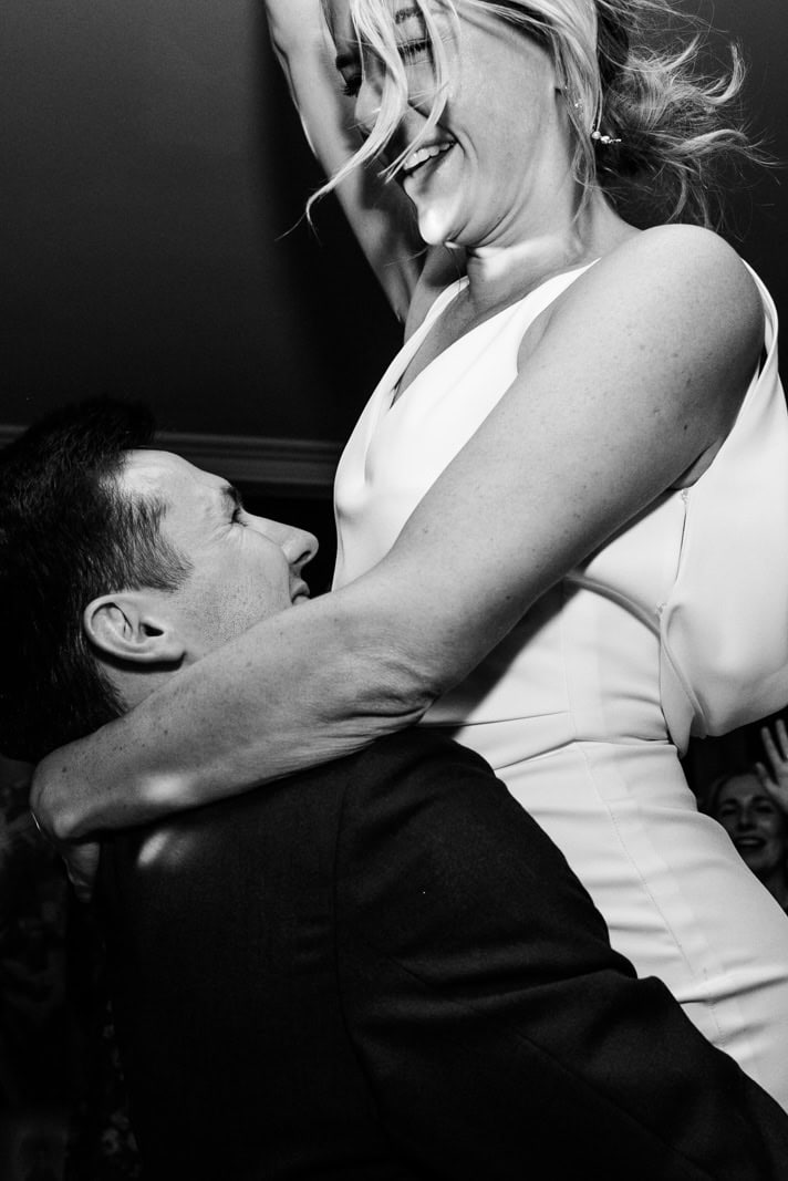 A bride laughs while dancing with her partner