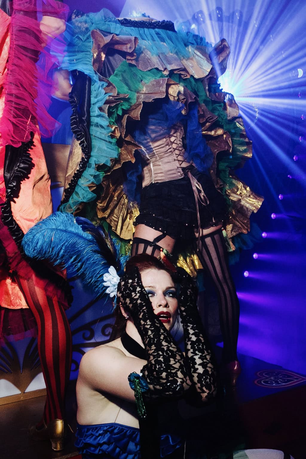 A costumed performer hangs upside down under colourful stage lights