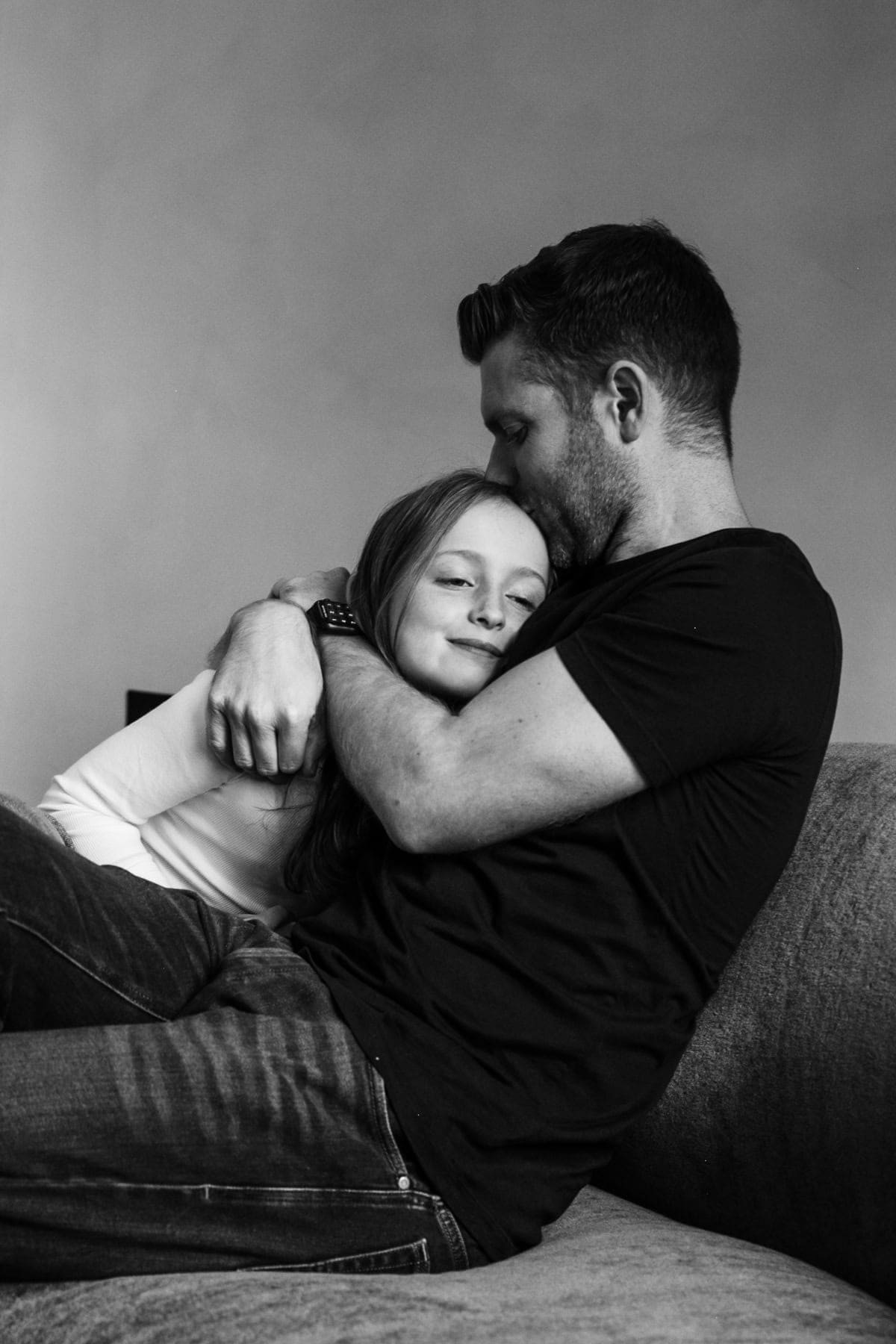 A father and daughter hold one another on a sofa