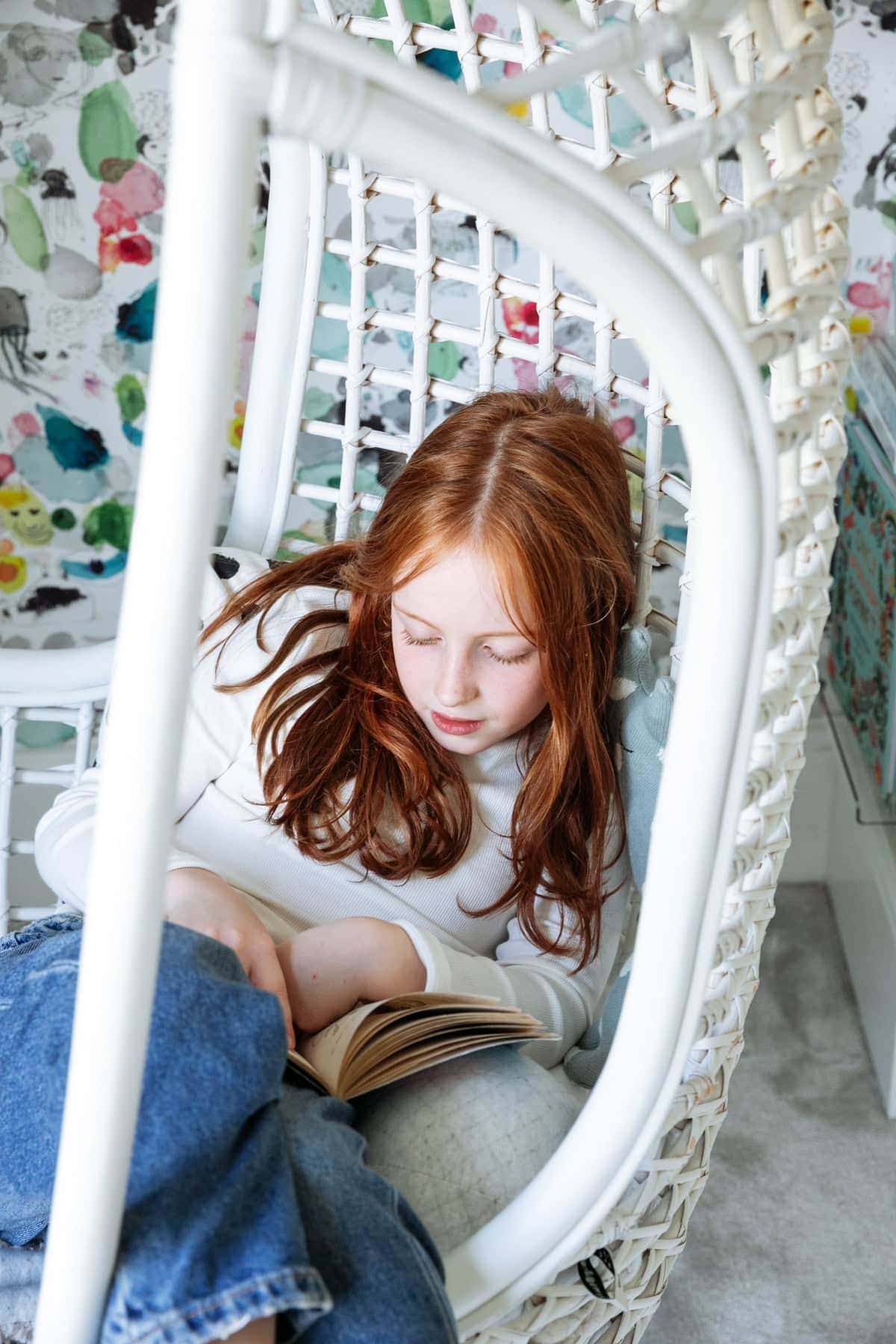 A girl sits sideways in a white garden chair