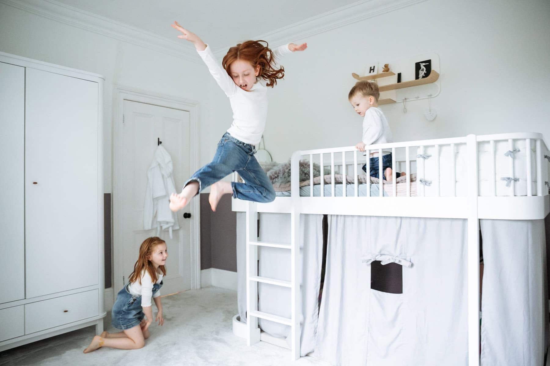 A child jumps from a bed while two others watch