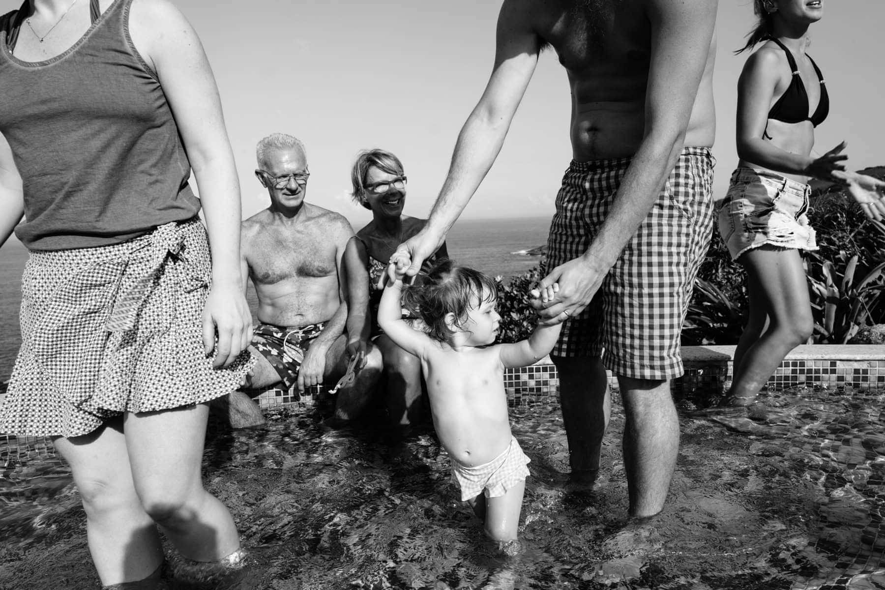 A small child stands among family beside a stream
