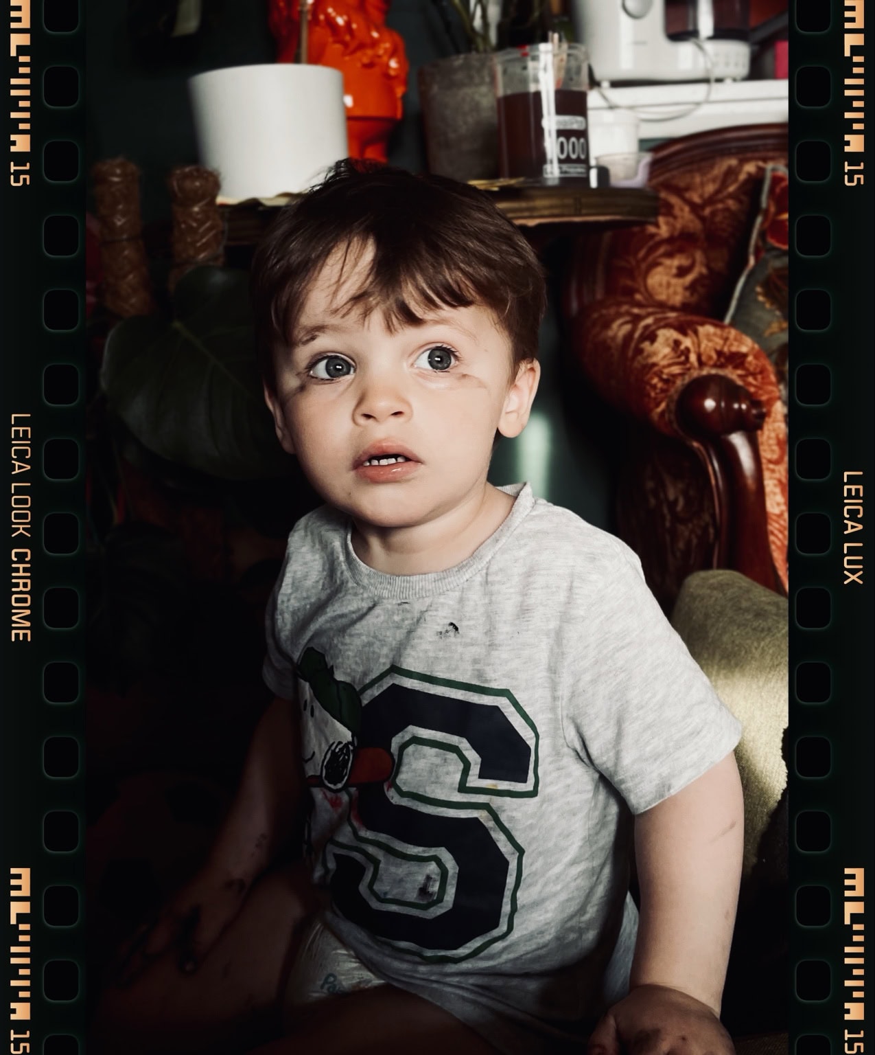 A wide-eyed child in a grey T-shirt, with the original film rebate visible