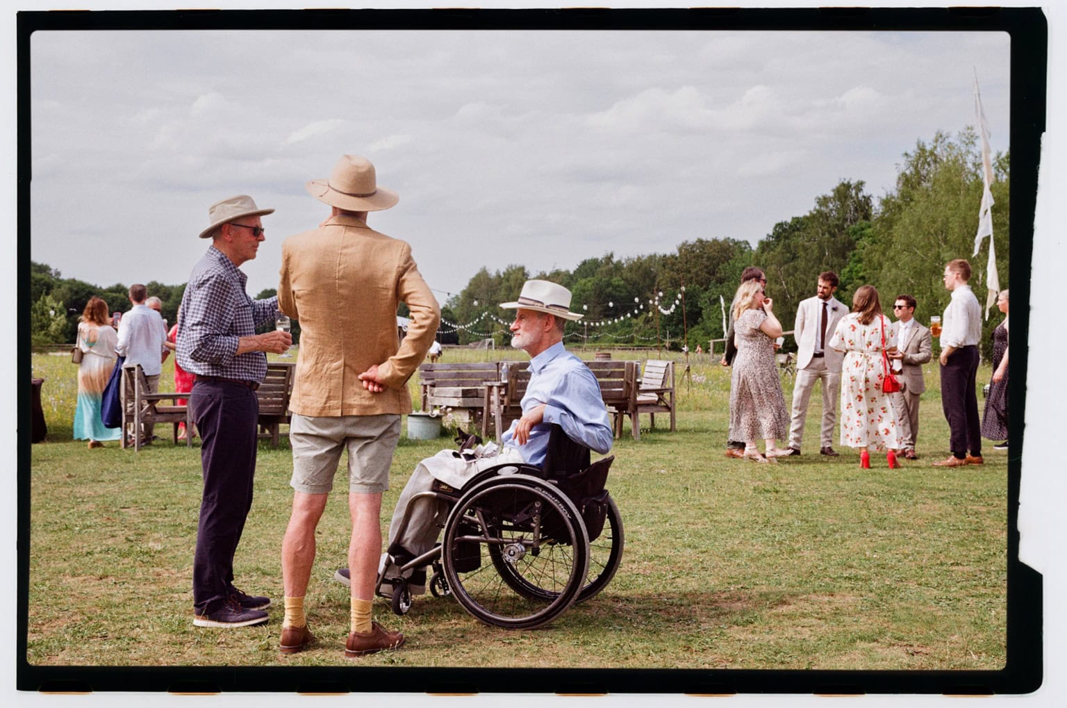 Guests talk in a garden with the original film border visible