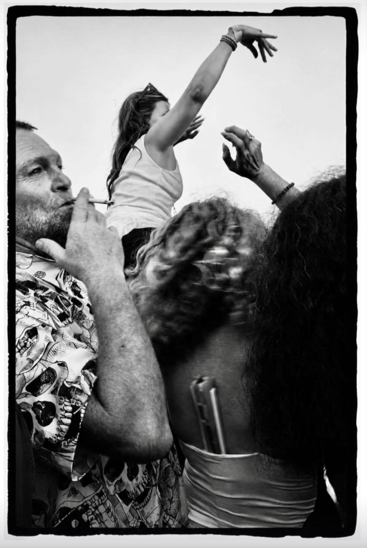 People reach toward one another in a black-and-white party photograph