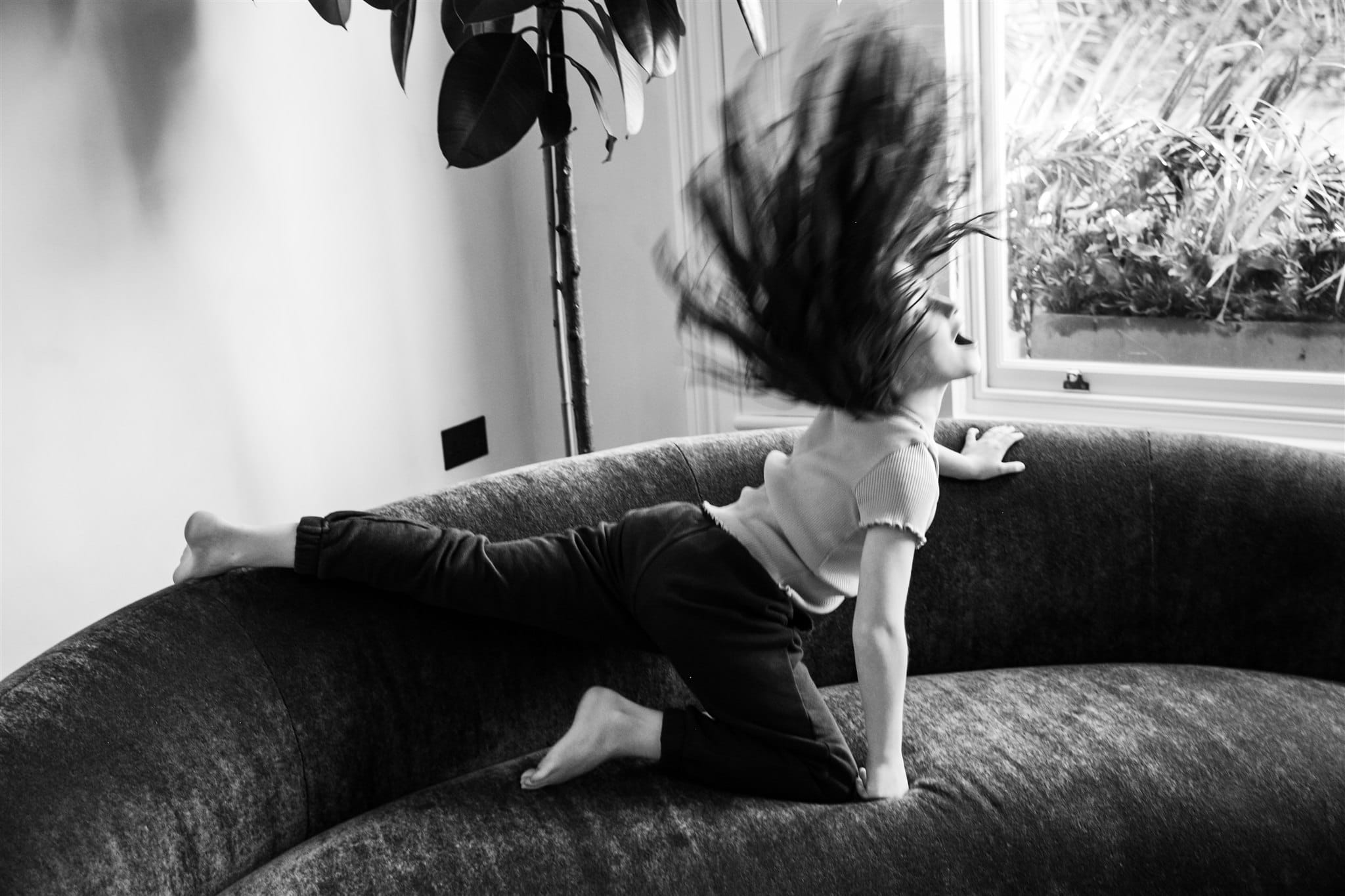 A child leaps on a sofa with hair flying