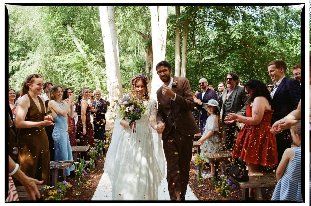 The newlyweds smiling as guests throw confetti