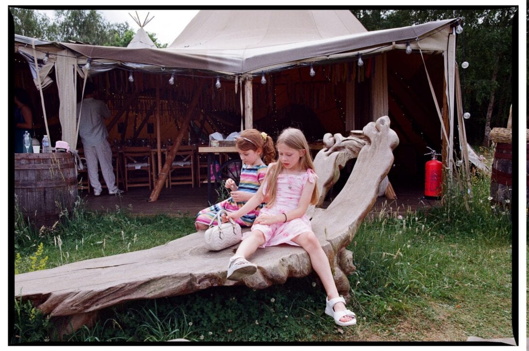 Two girls sitting on a carved wooden bench