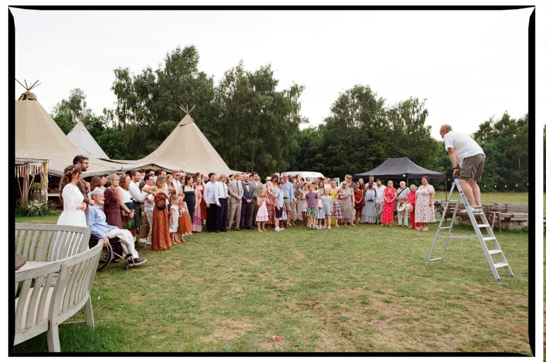 A large wedding group photograph with a guest on a ladder