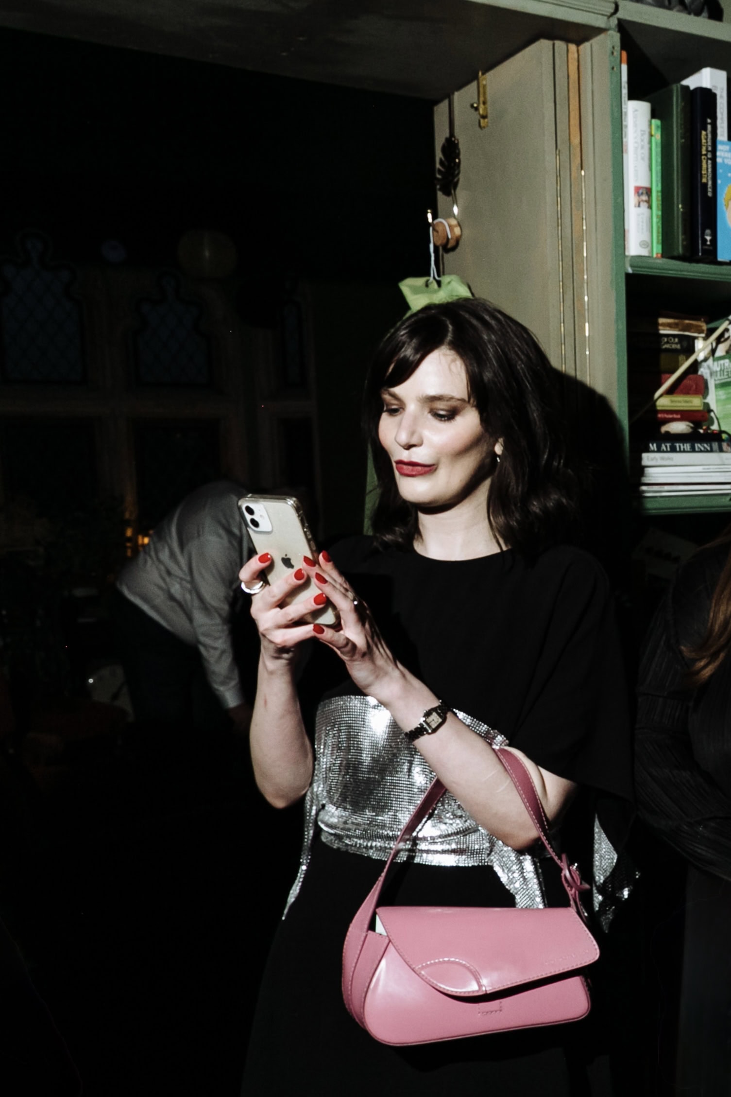 A woman in black looks at her phone at a party