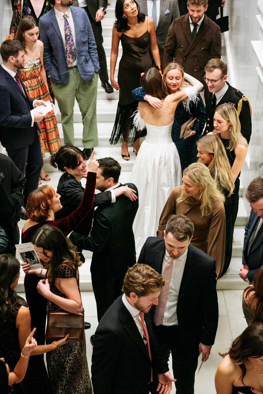Guests move through a crowded staircase around a bride