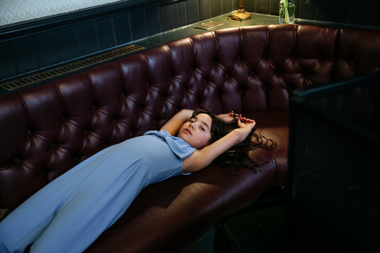 A woman reclines across a restaurant banquette