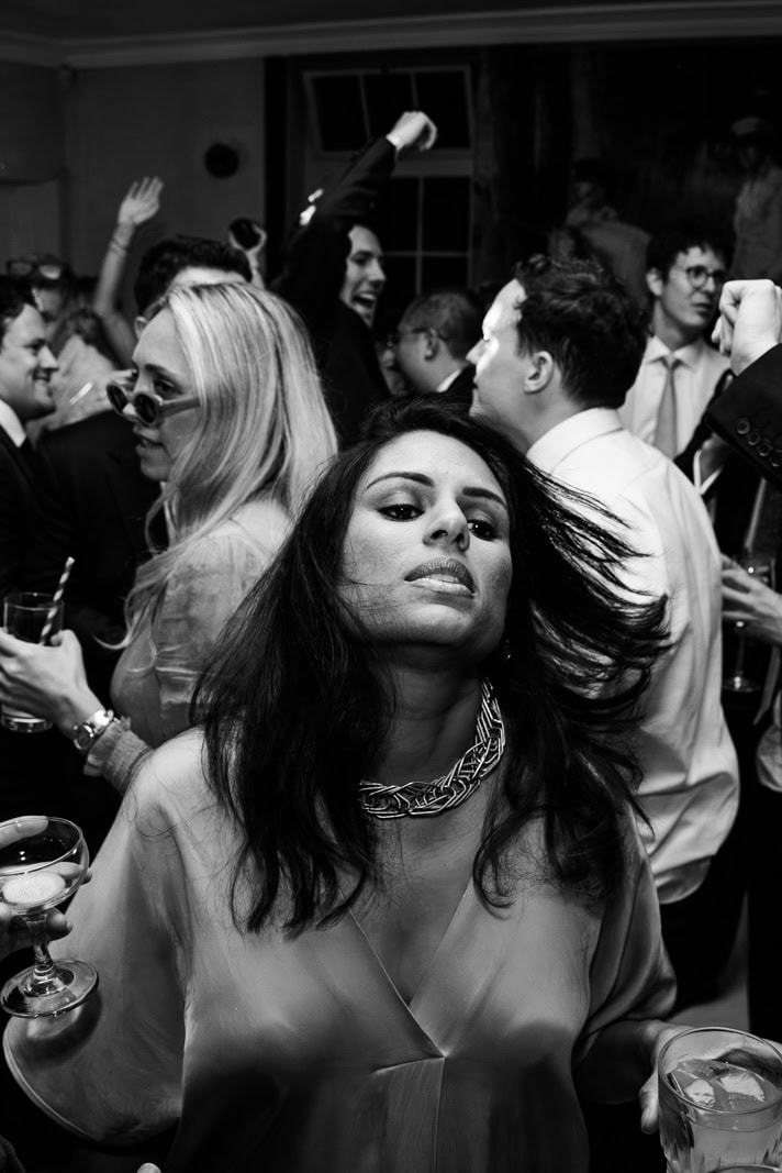 A woman dances with drinks in both hands in a crowded room