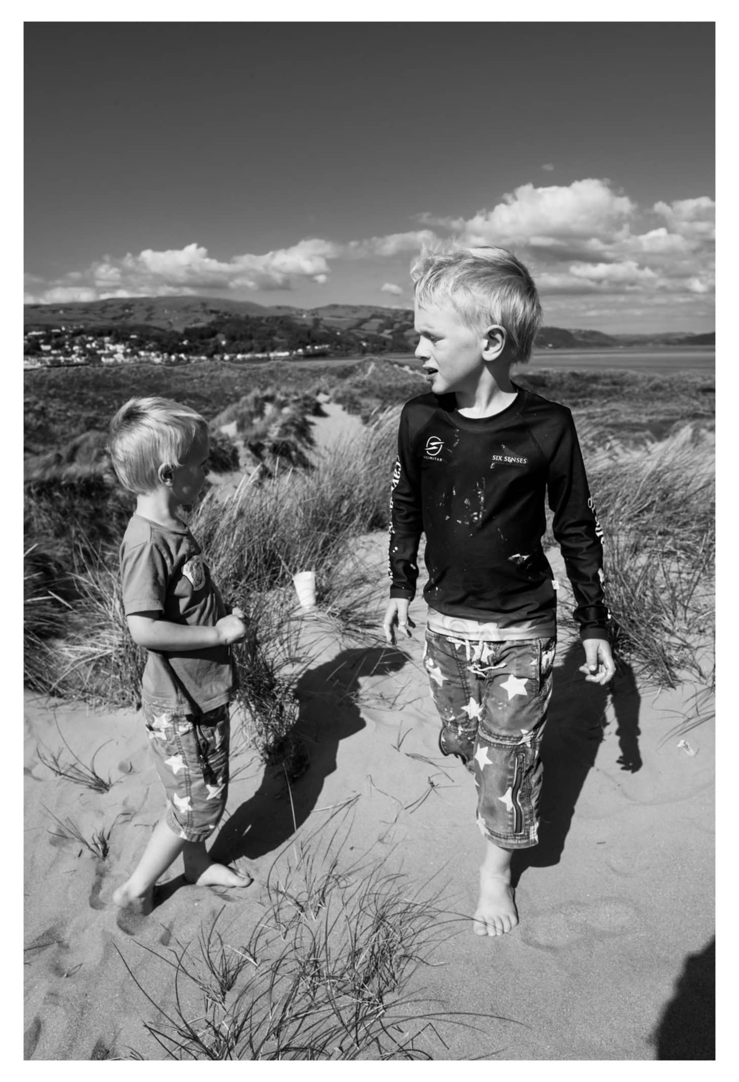 Two children walking together through sandy dunes
