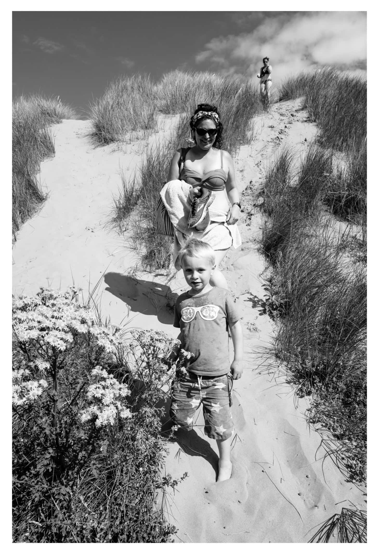 An adult and two children walking through coastal dunes