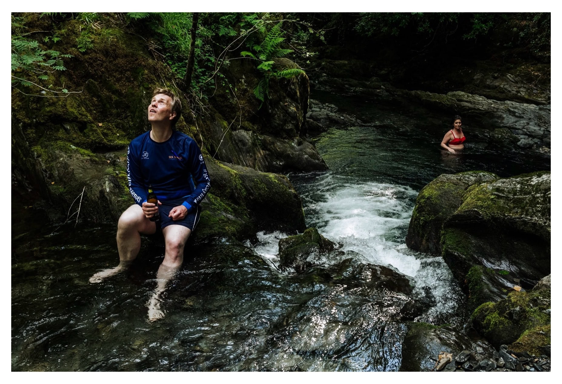 A child sitting on rocks at the edge of a stream