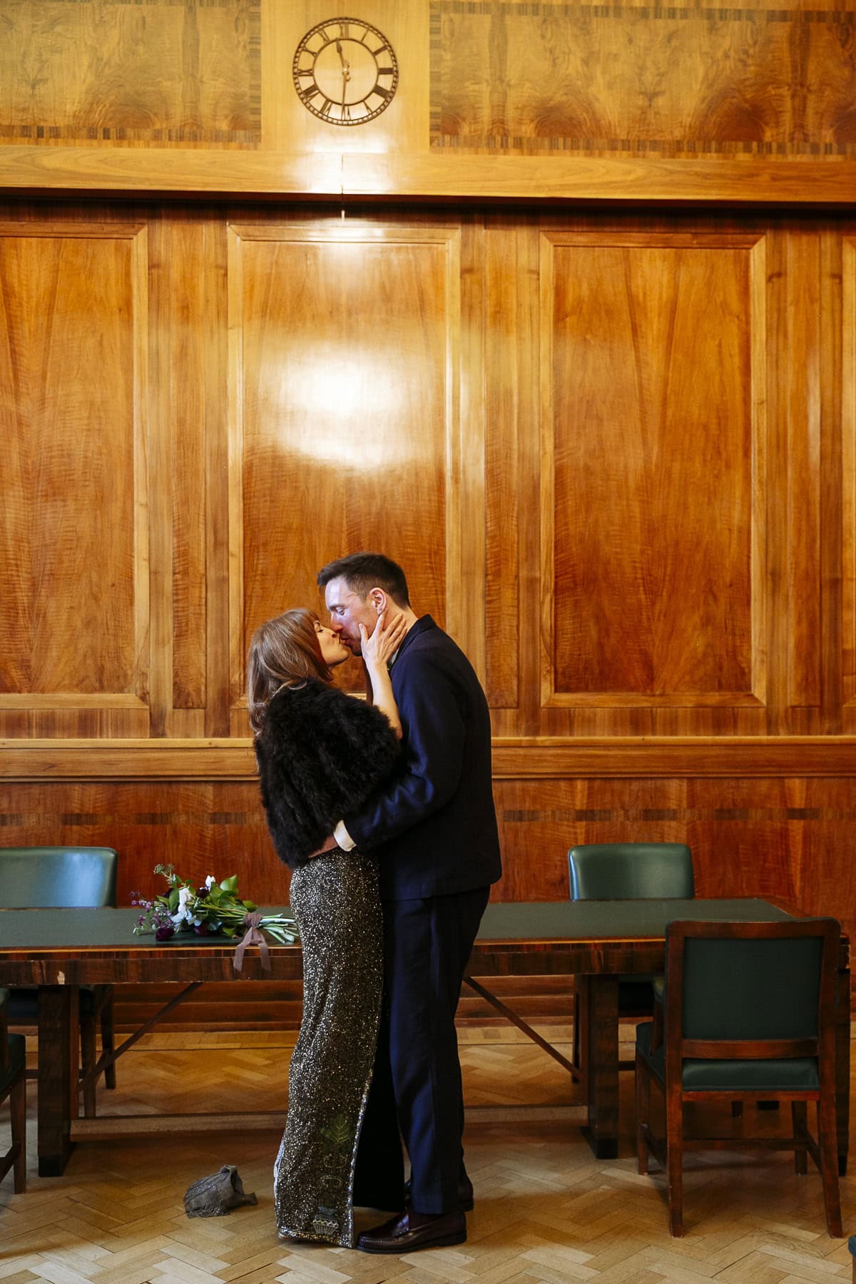 Ianthe and Patrick kissing beneath the ceremony room clock